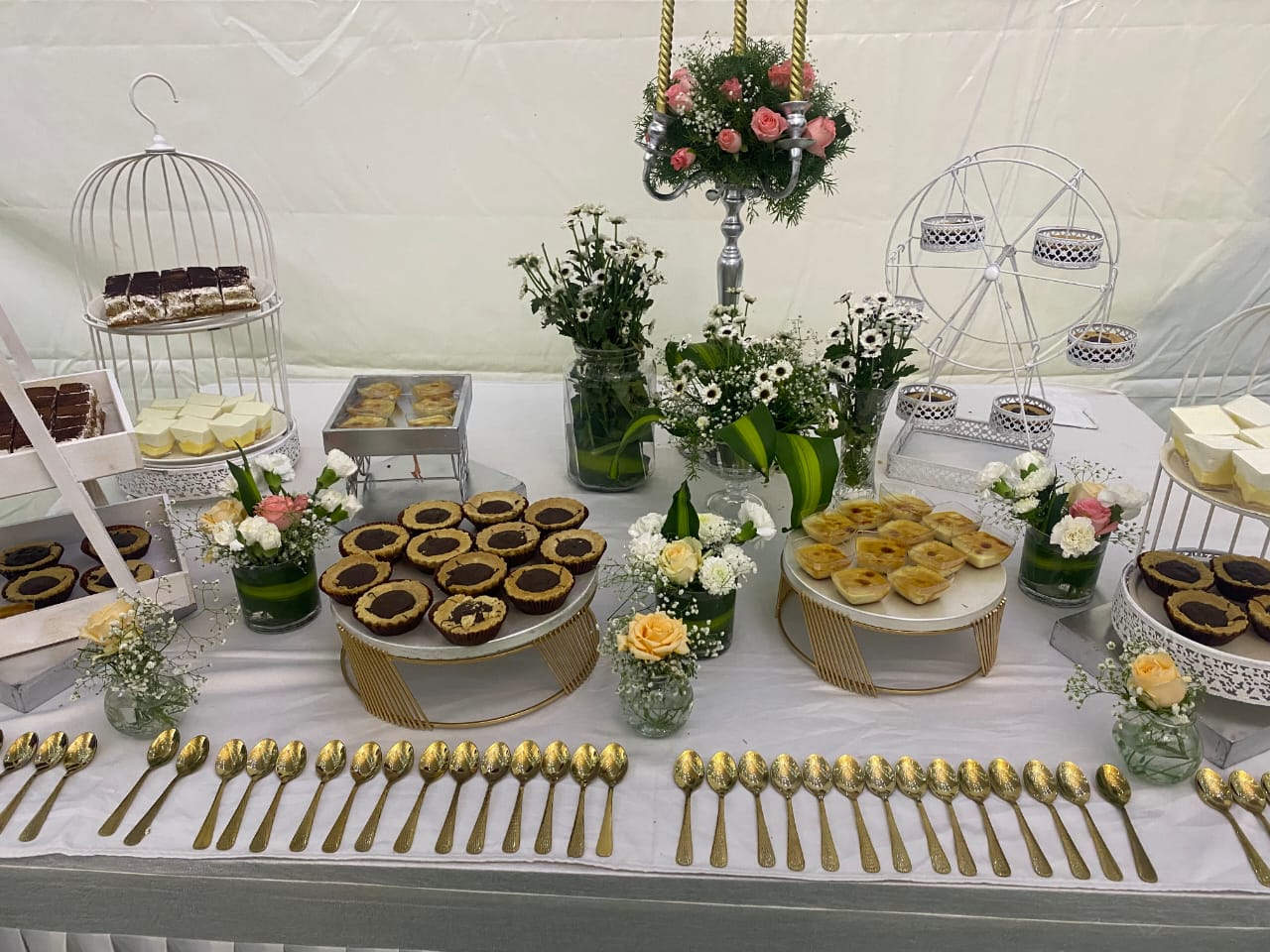 A floral dessert table with pastries and golden cutlery
